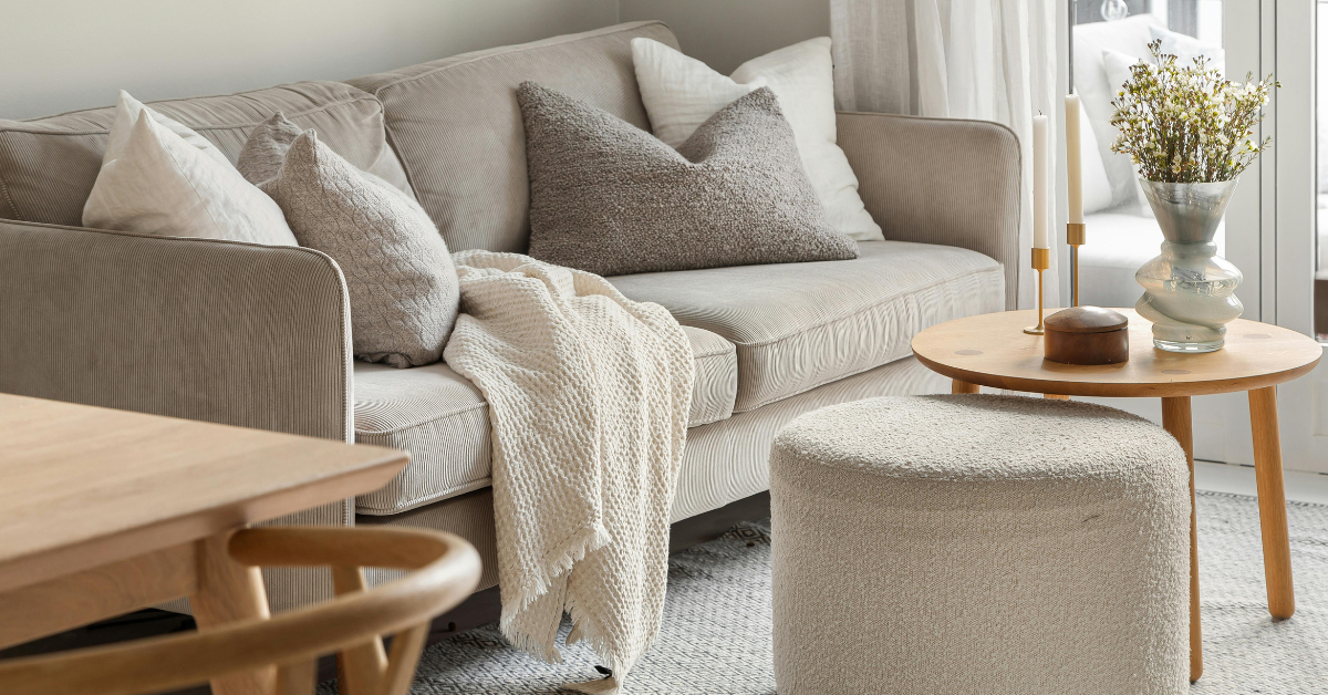 Beige sofa with throw, cushions and small coffee table