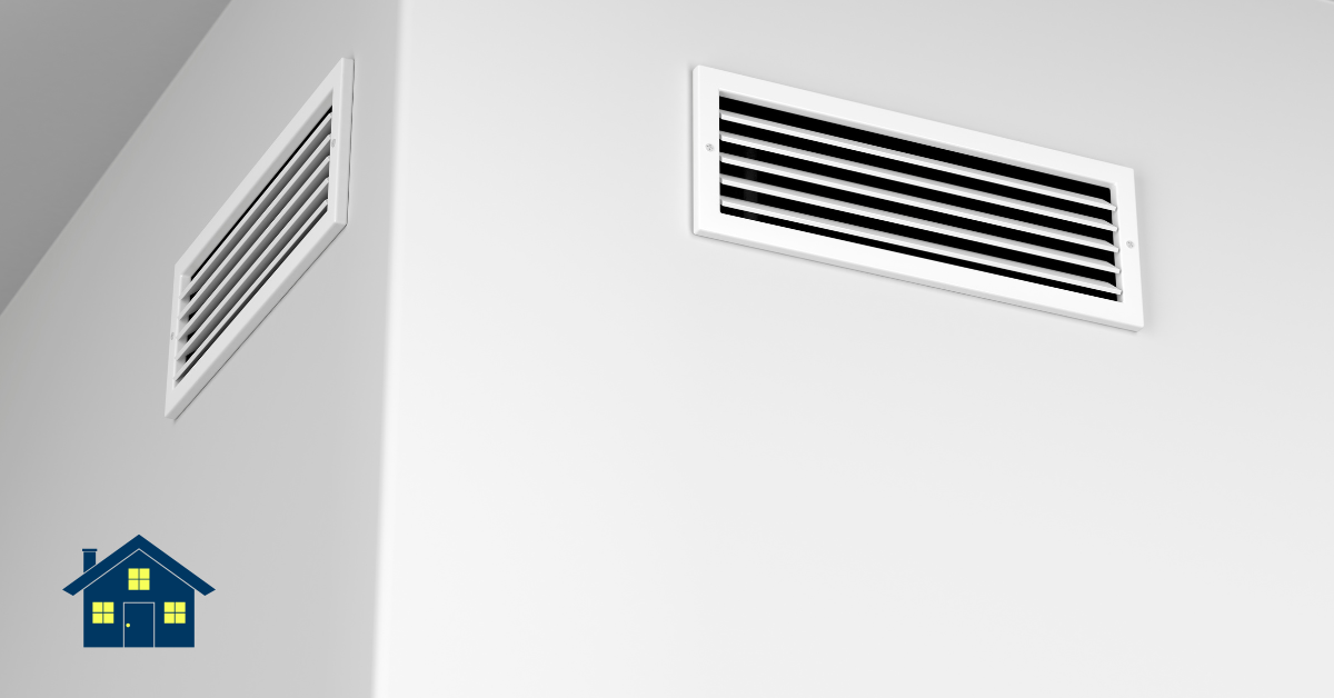 Two white ventilation grilles mounted high on adjoining walls, with a small blue house icon in the bottom-left corner.
