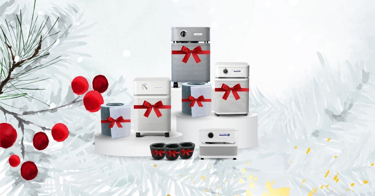 A photo showcasing Austin Air’s Breathe Better Blitz offerings, which includes four air purifiers and two replacement filters – all wrapped in red bows, over a wintery background.