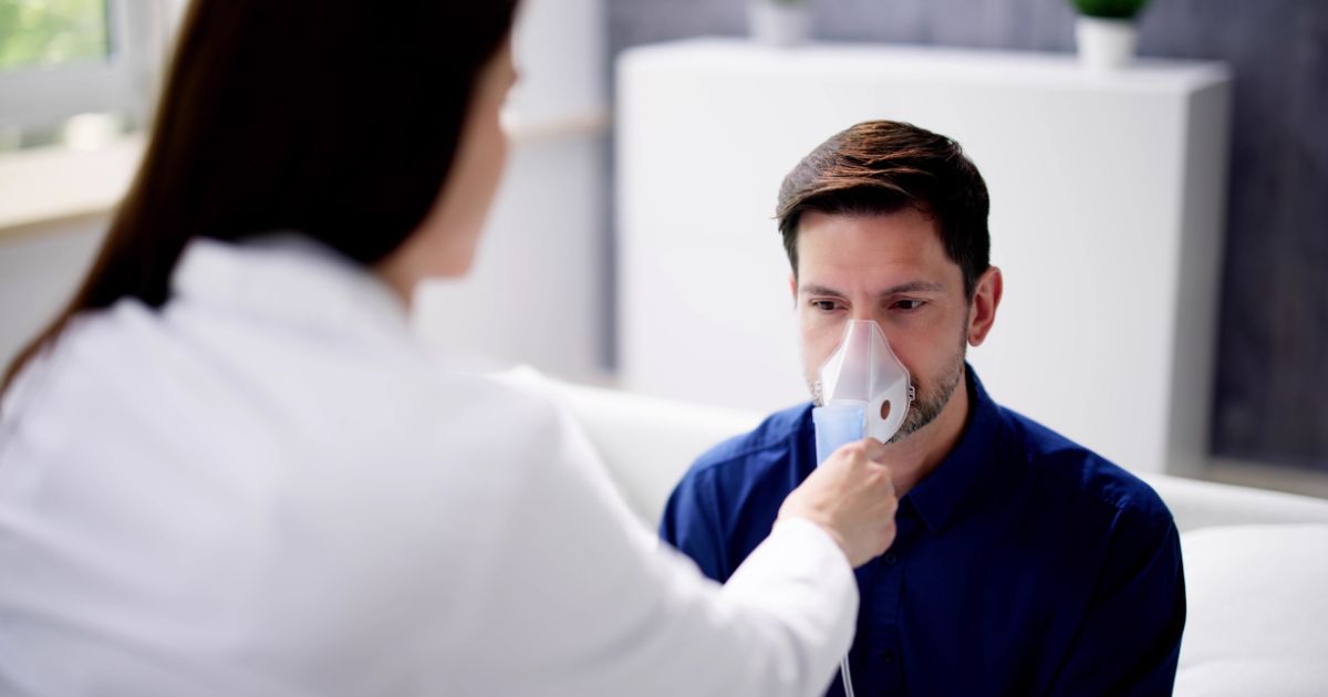 Female doctor placing a nebulizer on male patient.