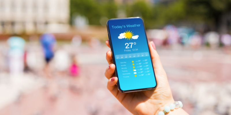 Hand holding a smart phone that displays the weather forecast