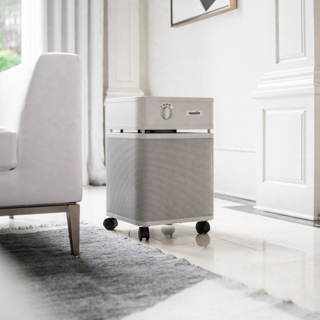 Austin Air HealthMate air purifier on a white floor in a modern living room
