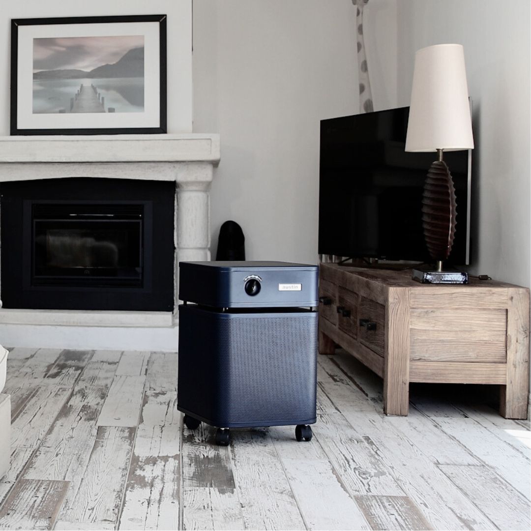 Midnight blue Austin Air purifier in a living room setting near fireplace and TV.