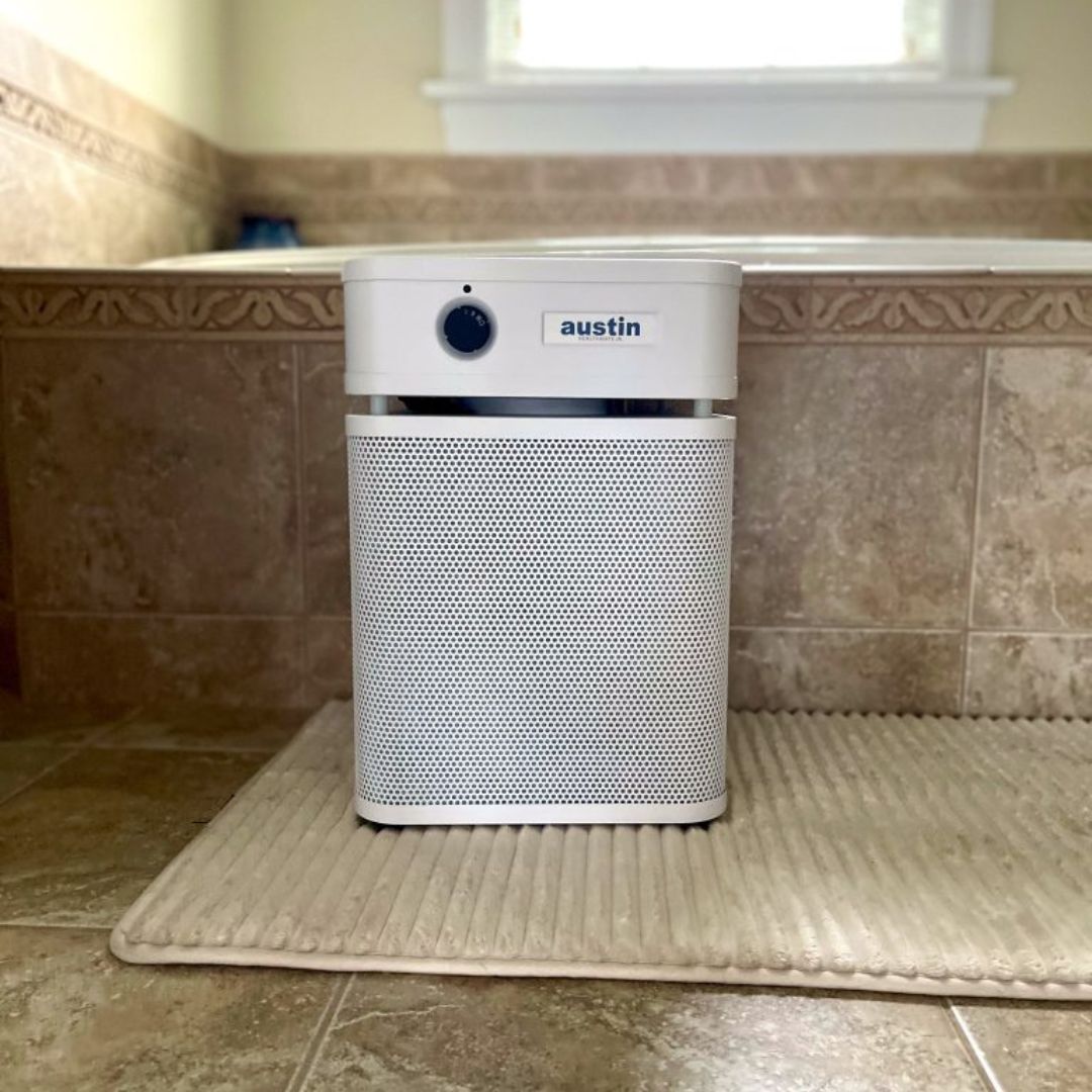 austin air healthmate junior air purifier on a bath mat in a bathroom setting