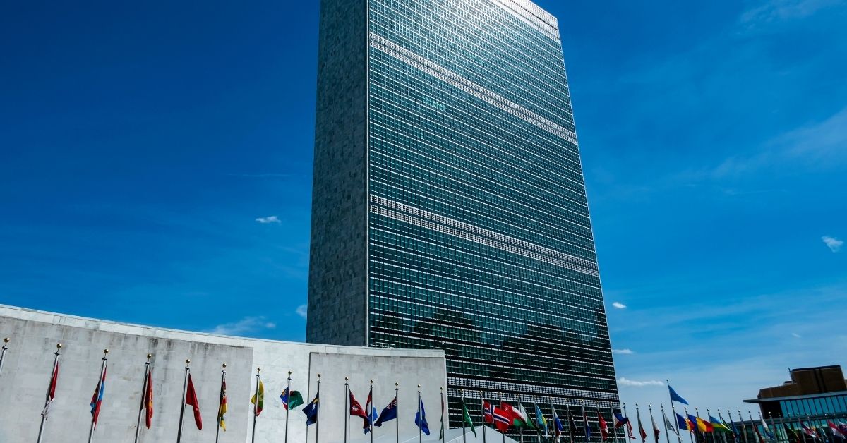 A photo of the United Nations headquarters in New York City – it is a large skyscraper with flags of member nations at the base.