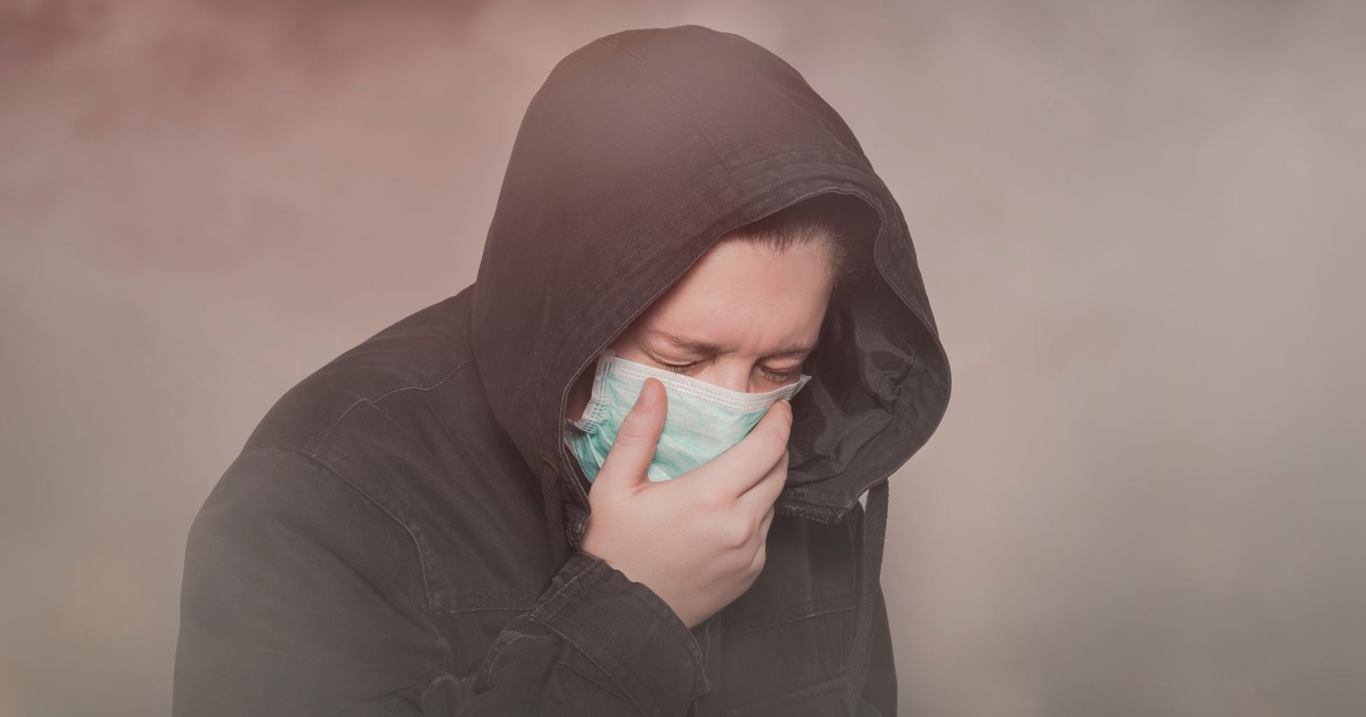Person in smoke filled air, wearing a facemask and coughing 