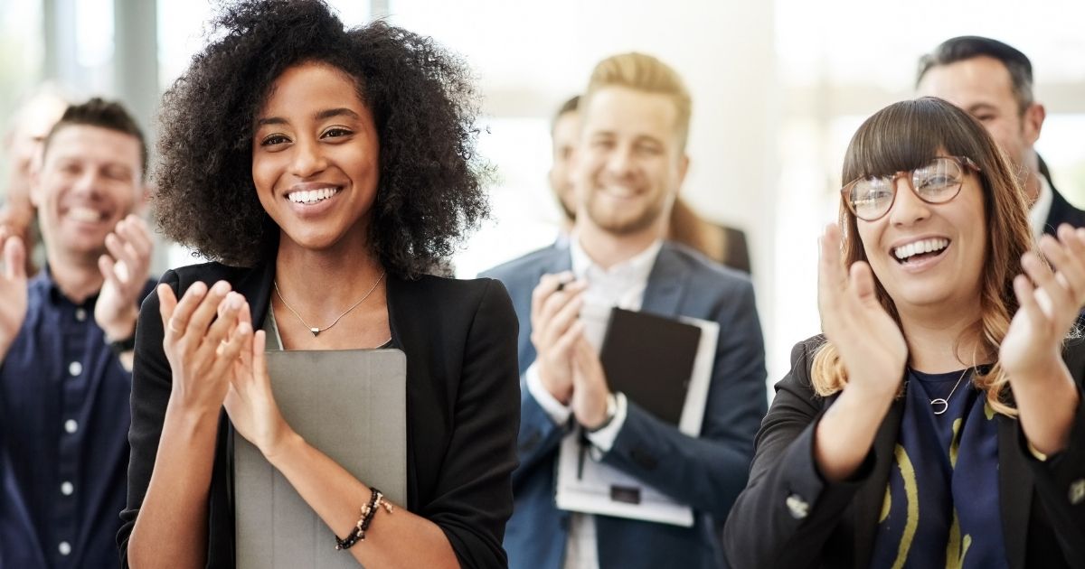 A group of office workers clapping and smiling