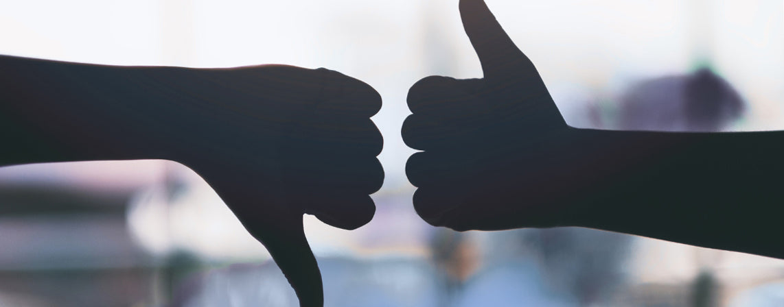 Two hands in shadow. One with thumb down, one with thumb up.