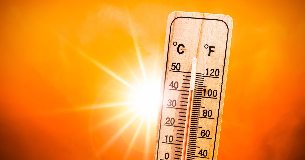 Thermometer shows high temperature with sun shining in the background