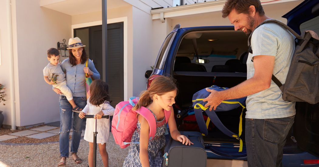 Family putting bags in the car to go on holiday