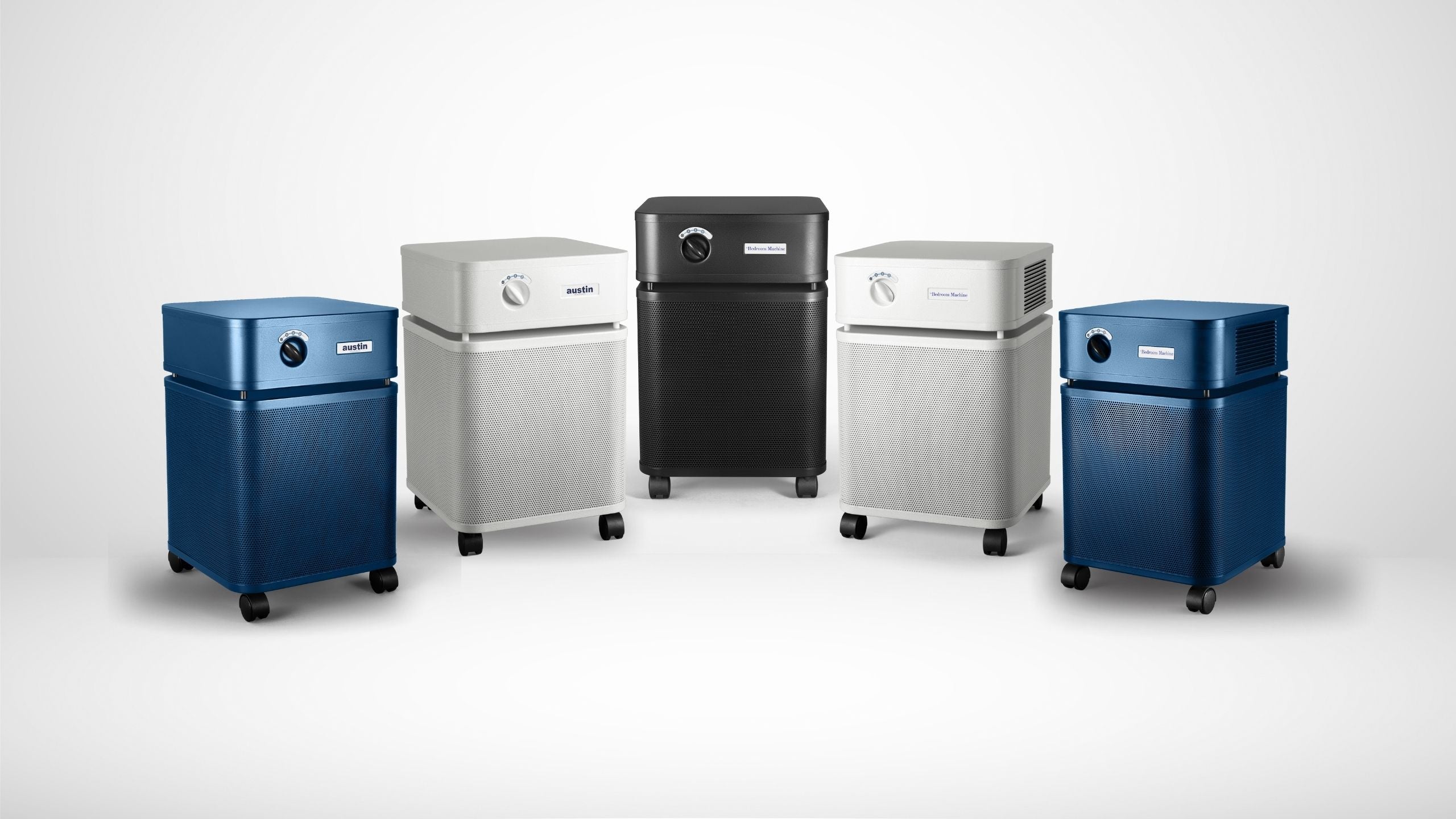 4 Standard Austin Air purifiers in home settings: sandstone Bedroom Machine, with white, midnight blue, and black HealthMates
