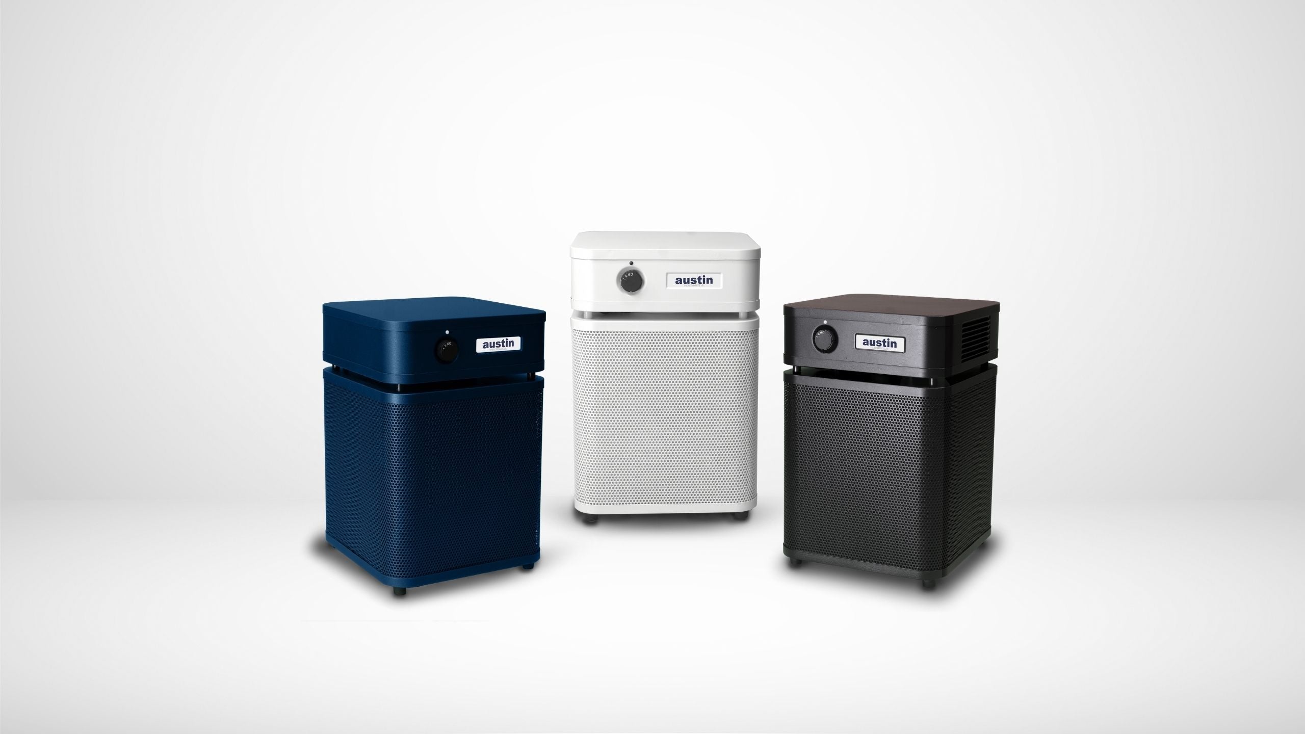 4 Austin Air Junior purifiers featured in various home settings, includes sandstone, white, midnight blue, and black models