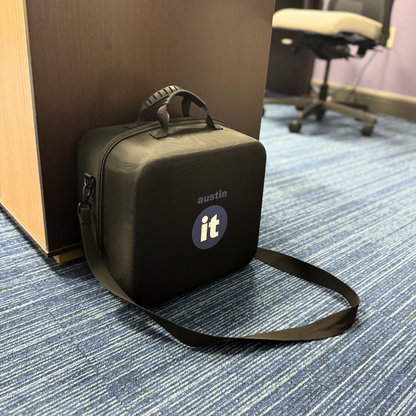 Austin air it Black carrying case with 'austin it' logo on a blue carpeted floor.