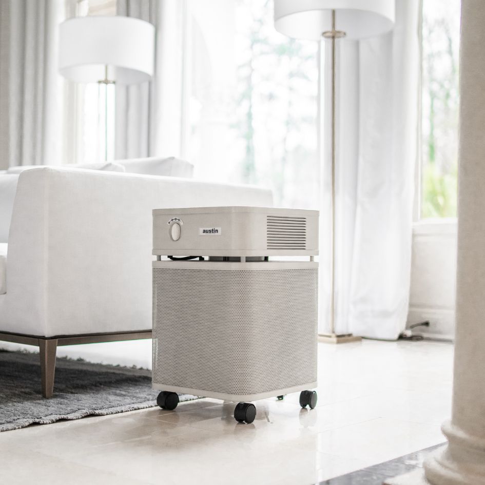 Portable air purifier in a room with white furniture and curtains