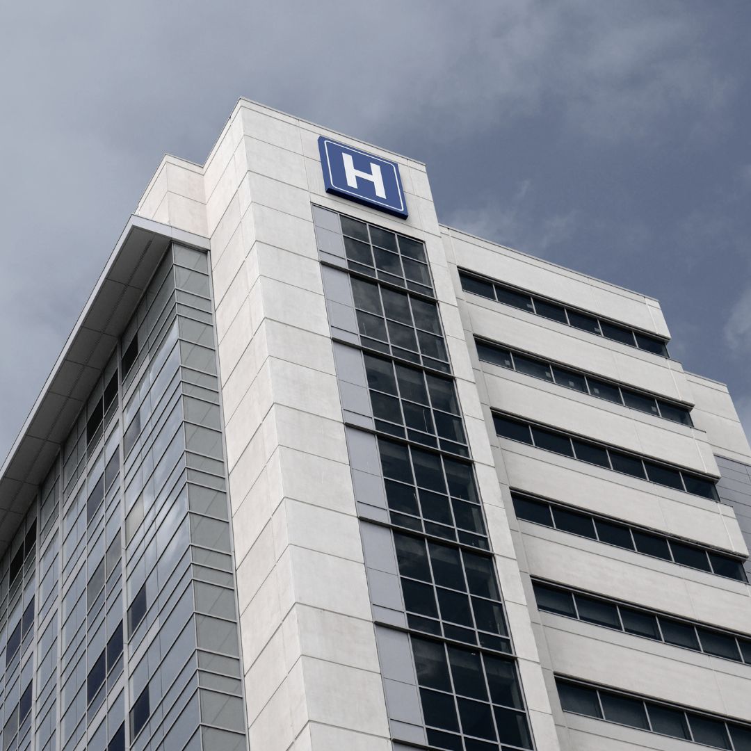 Tall medical building with a prominent 'H' logo on a cloudy day