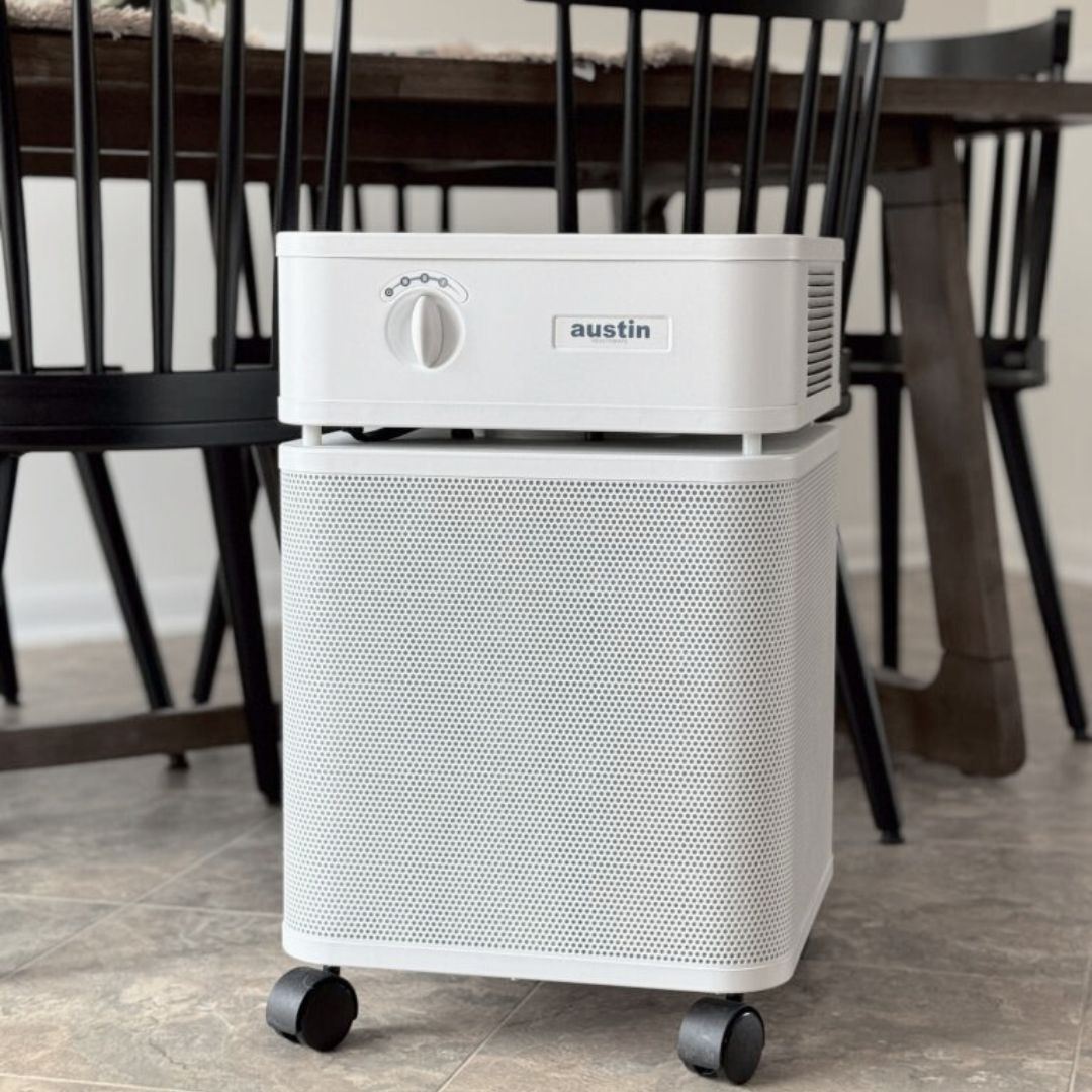 White Austin Air purifier in a kitchen on a tiled floor.