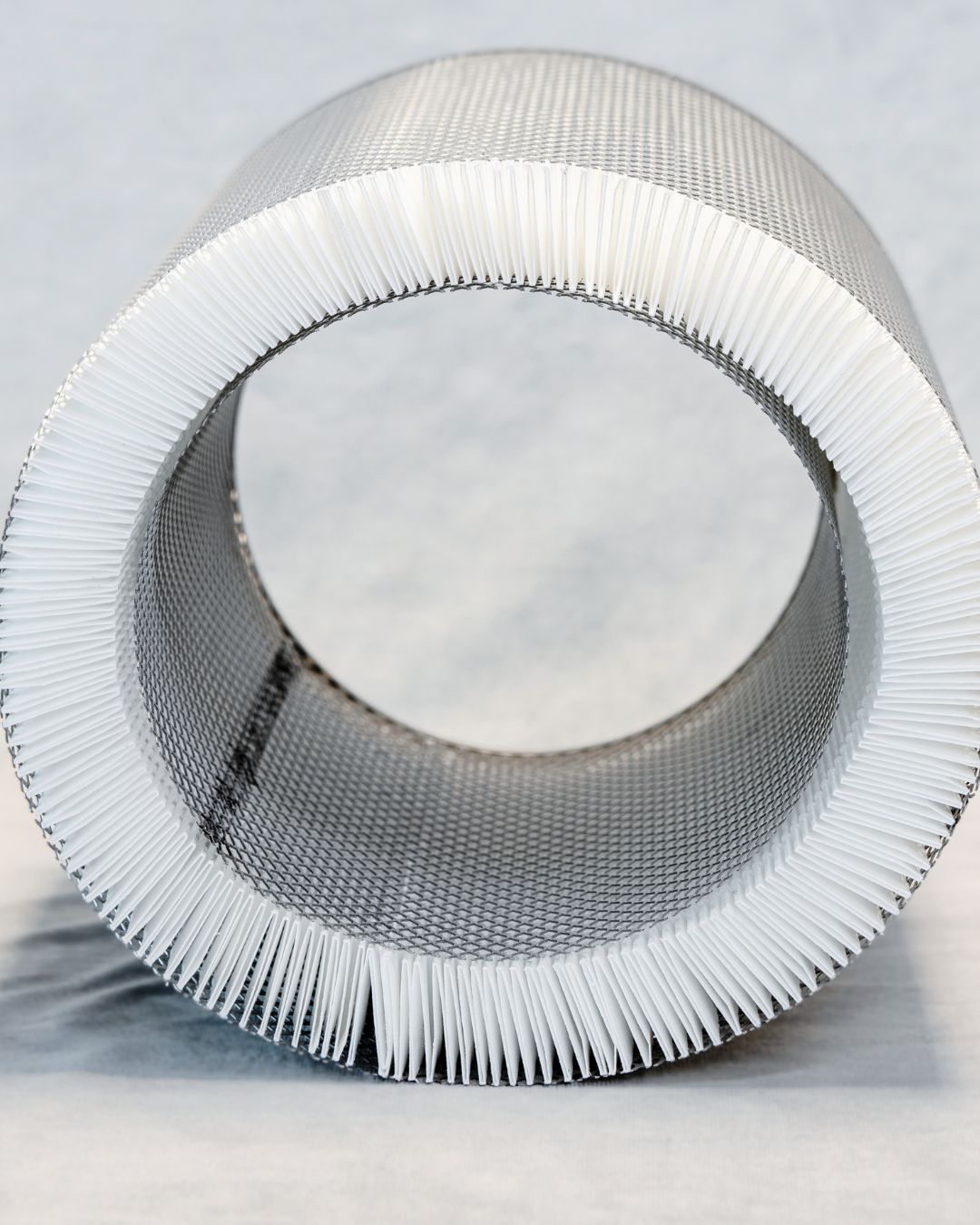 Close-up of a metallic filter with white mesh on a light gray background