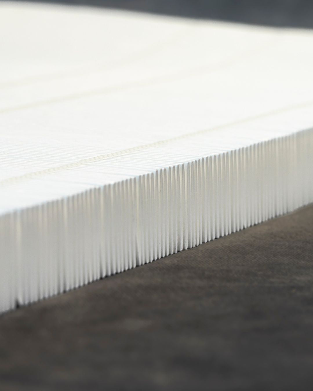 Close-up of a white strip of accordion HEPA paper on a dark gray surface
