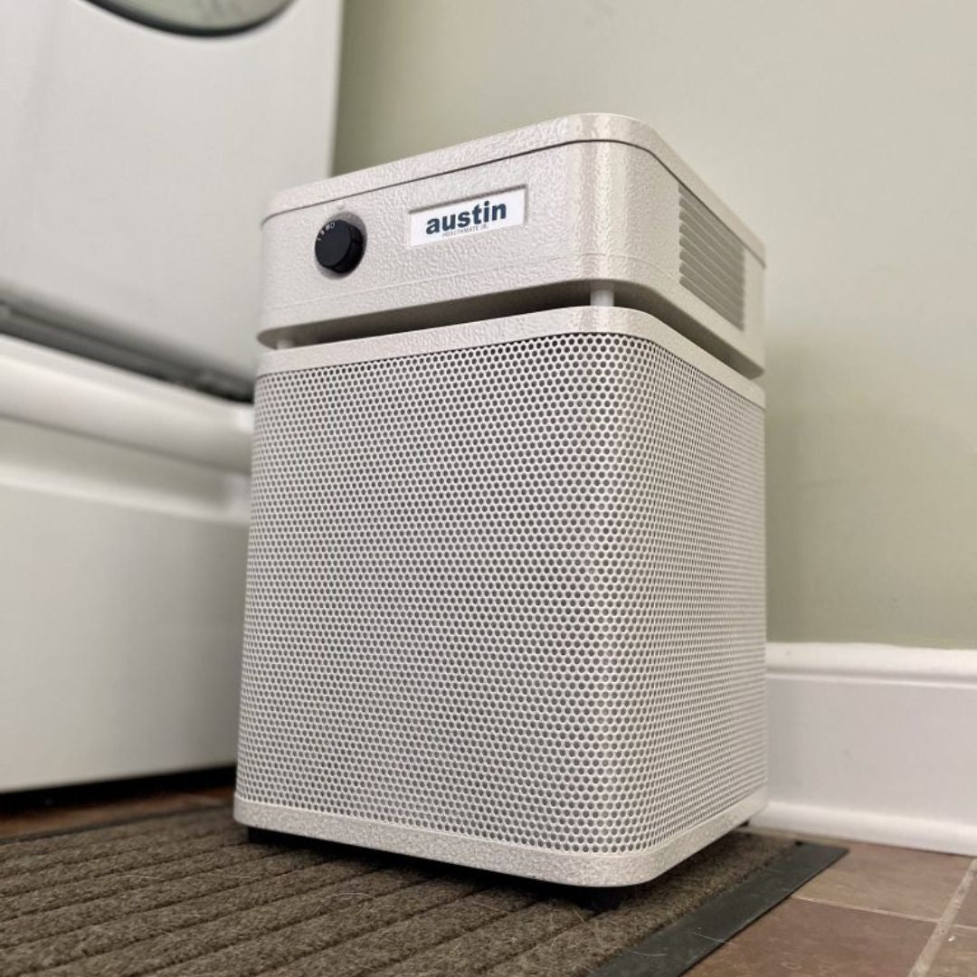 austin air healthmate junior white air purifier with 'austin' branding on a carpeted floor.