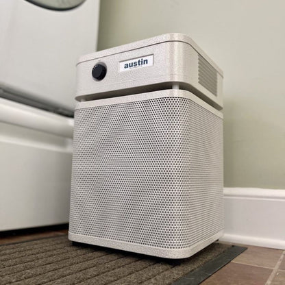 austin air healthmate junior white air purifier with 'austin' branding on a carpeted floor.