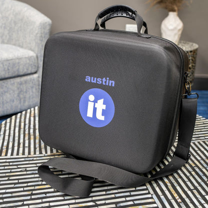 Austin "it" black carrying case with 'austin it' logo on a patterned rug