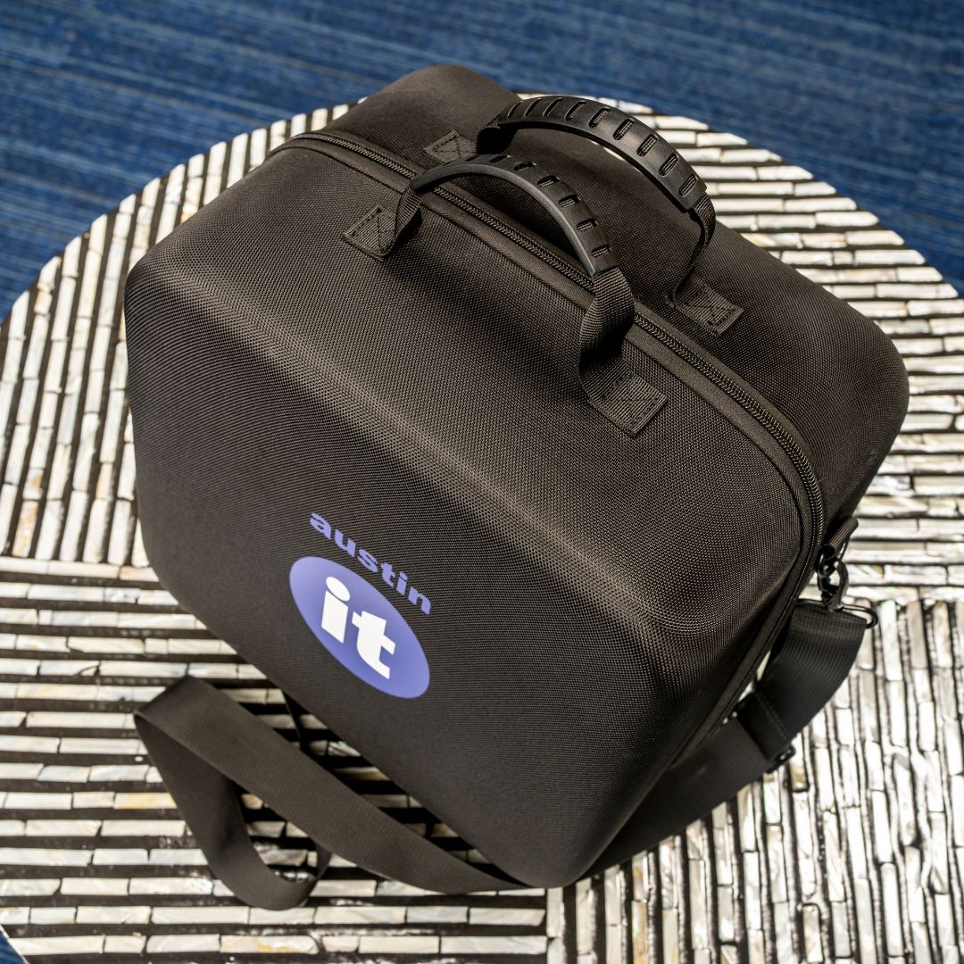 Austin air "it" air purifier in a  lack carrying case with 'austin it' logo on a textured surface
