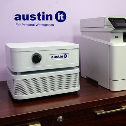 Austin air "it" with 'austin it' branding on a desk against a purple wall.